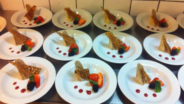 Flade tallerkener med dessert bestående af sprøde vafler, frugt og bær, anrettet med sauce.