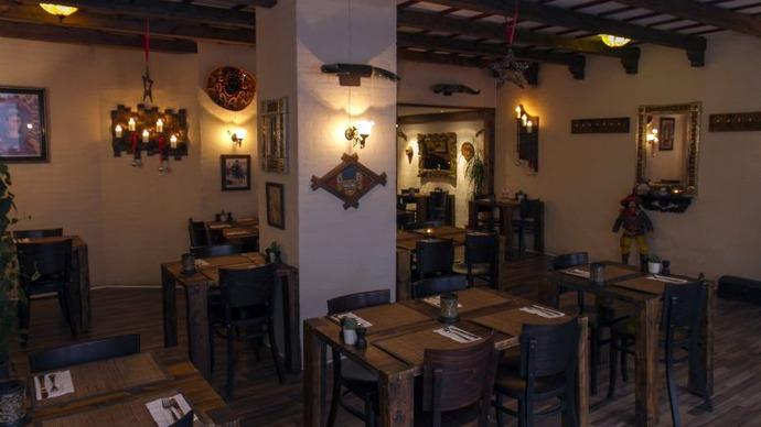 En hyggelig restaurant med træborde, stole og dæmpet belysning, der skaber en varm atmosfære.