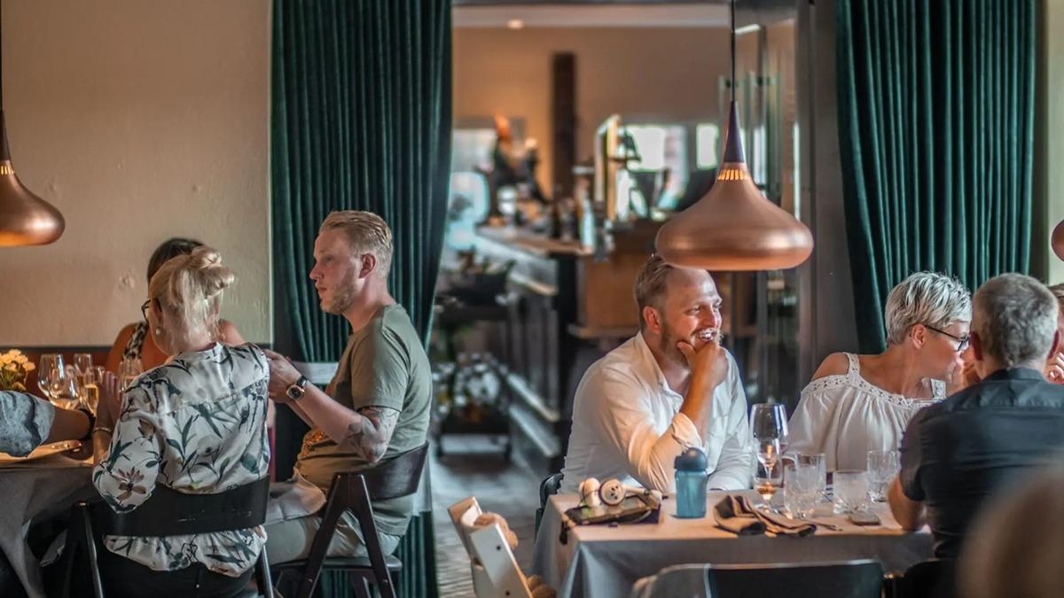Gæster nyder middag i en moderne restaurant med stilfuld indretning og dæmpet belysning.