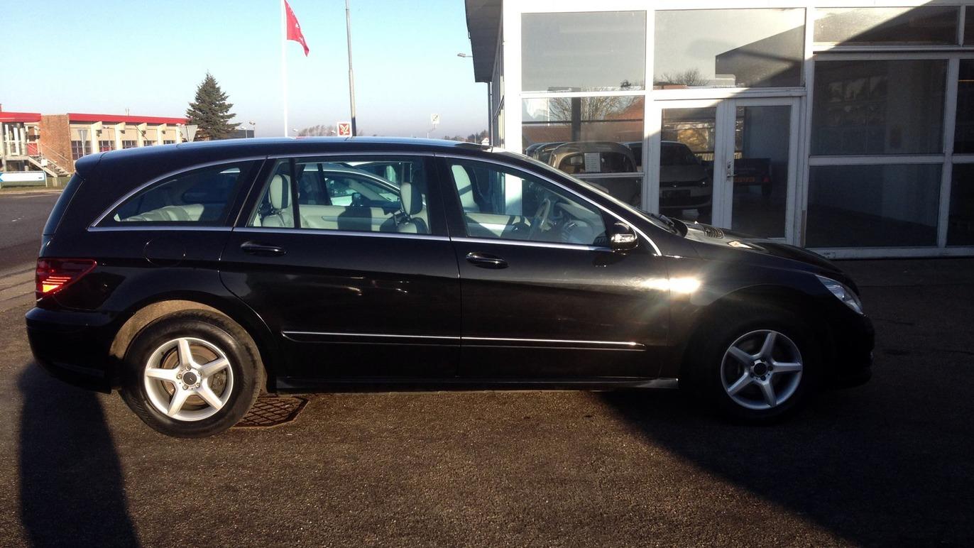 En sort stationcar parkeret foran en bygning med vinduer og en rød flag.