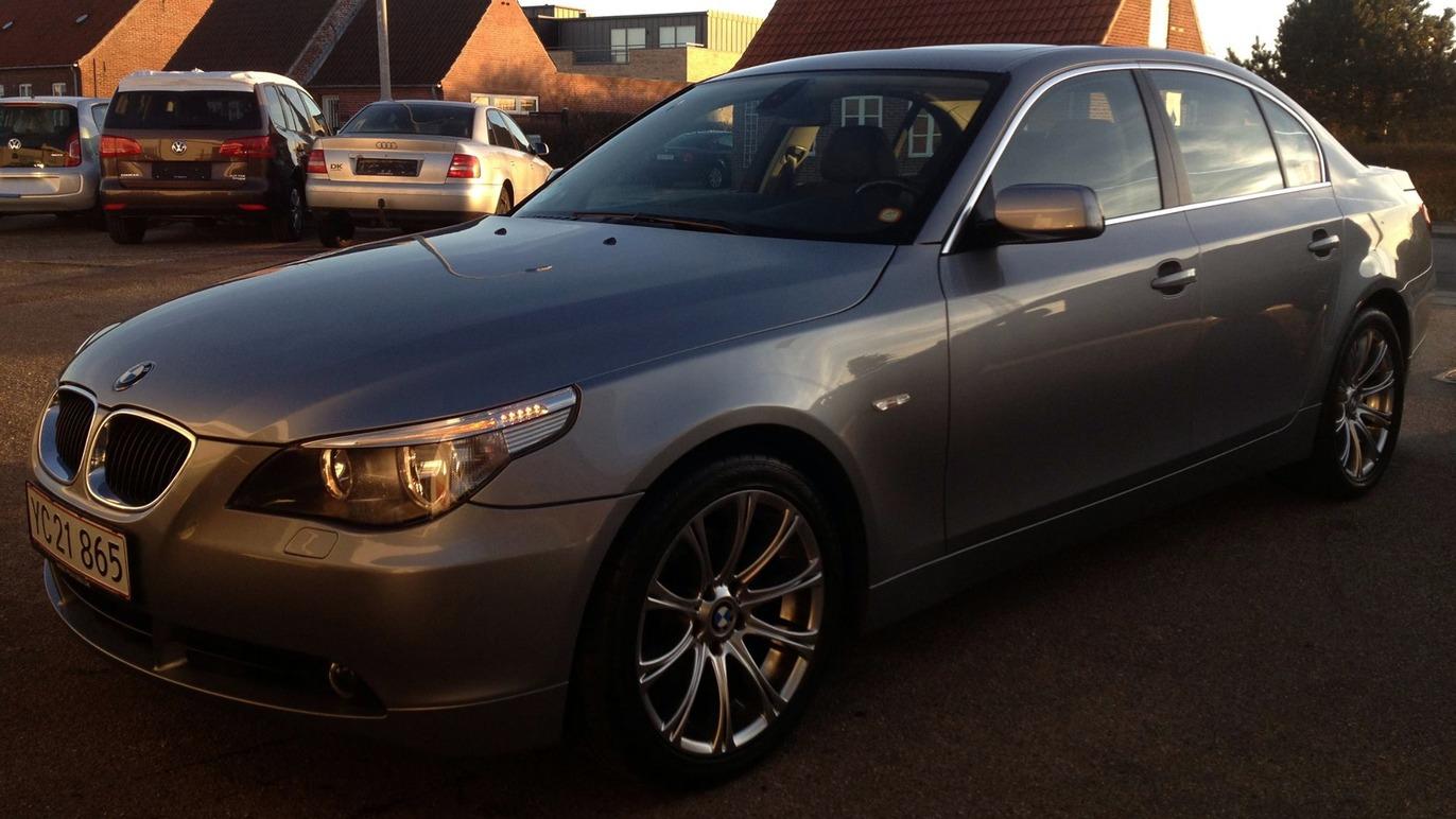 En sølvgrå BMW sedan parkeret på en parkeringsplads med biler i baggrunden.