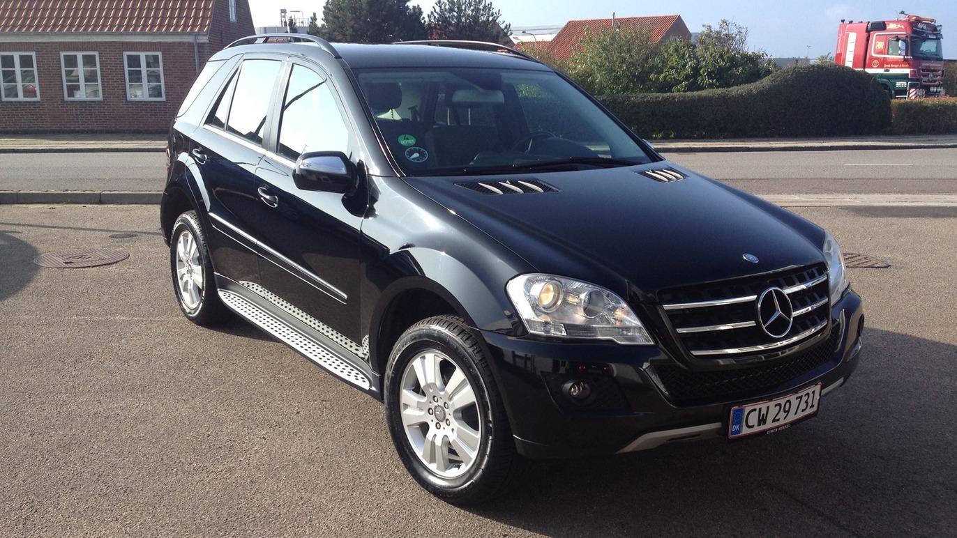 En sort Mercedes SUV parkeret på en vej med bygninger i baggrunden.