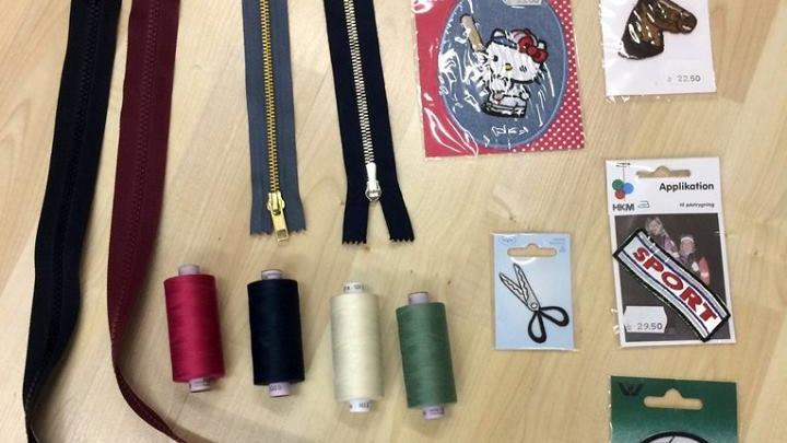Billede af sytilbehør med tråde, lynlåse, applikationer og broderi til kreative projekter.