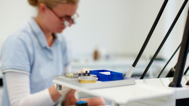 En laboratorietekniker arbejder med prøver og udstyr i et moderne laboratorium.