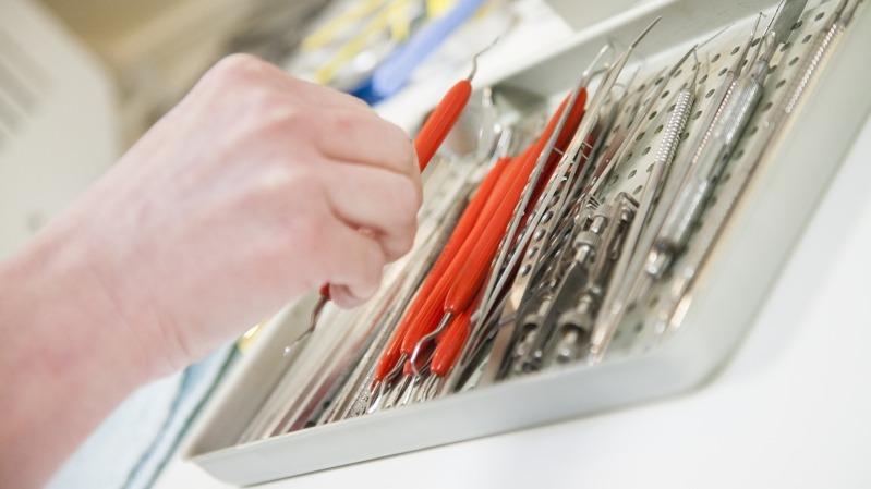 En hånd, der griber fat i et redskab fra en skuffe fyldt med forskellige værktøjer og instrumenter.