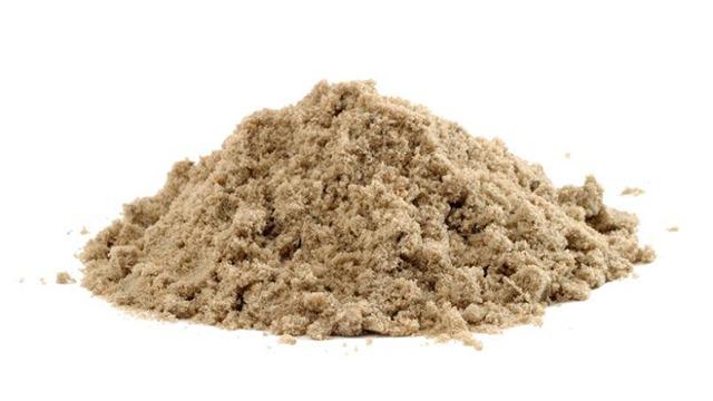 En bunke sand på hvid baggrund, der viser den fine tekstur og farve af sandet.