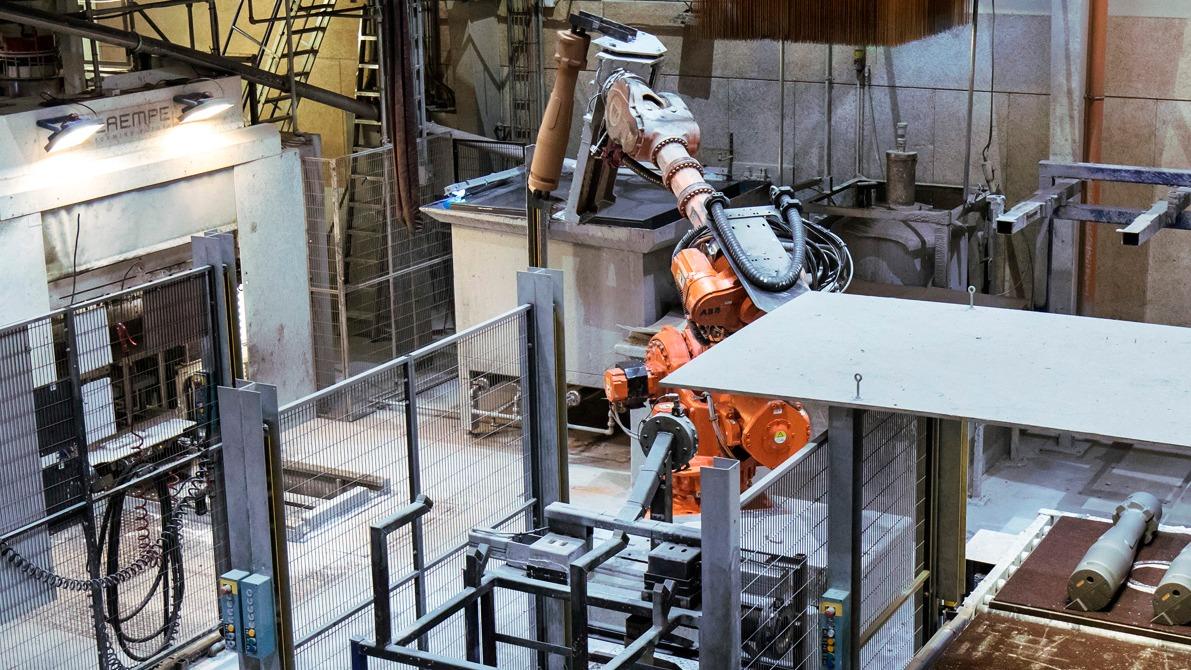 Industriel robotarm arbejder i en fabrik med metalbearbejdning og automatisering.