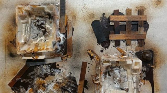 Et kunstværk med rustne metaldele og brændte materialer, der skaber en dramatisk og tekstureret komposition.
