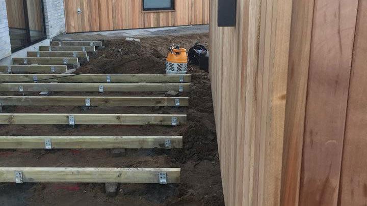 Trærammer til en trappe under konstruktion ved en bygning med træbeklædning.