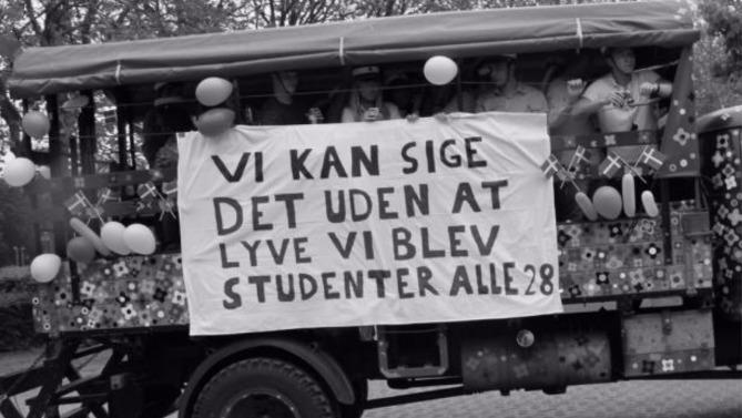 Studenterkørsel med banner, der siger "Vi kan sige det uden at lyve, vi blev studenter alle 28" og farverige balloner.