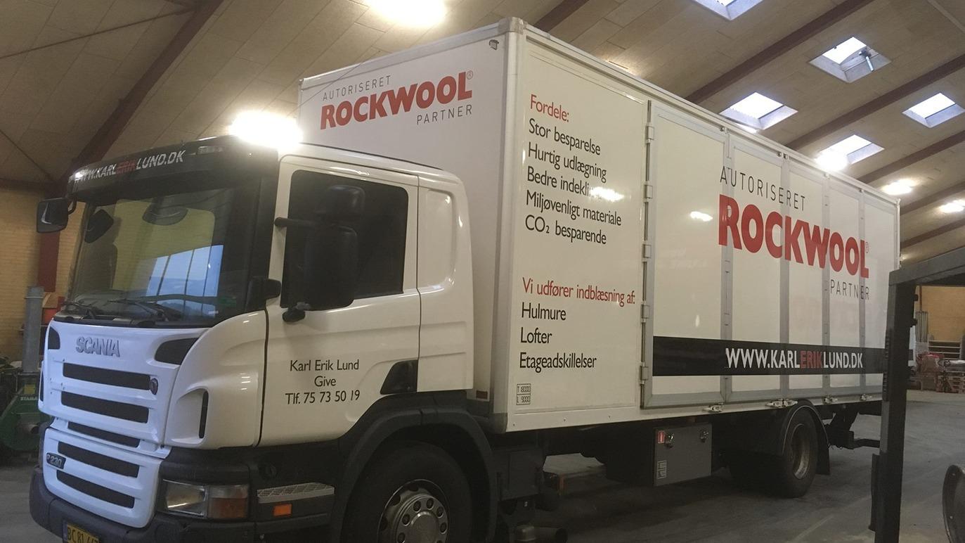 En hvid lastbil med Rockwool-logoet parkeret i en hal. Lastbilen har en stor kasse og synlige detaljer på siden.