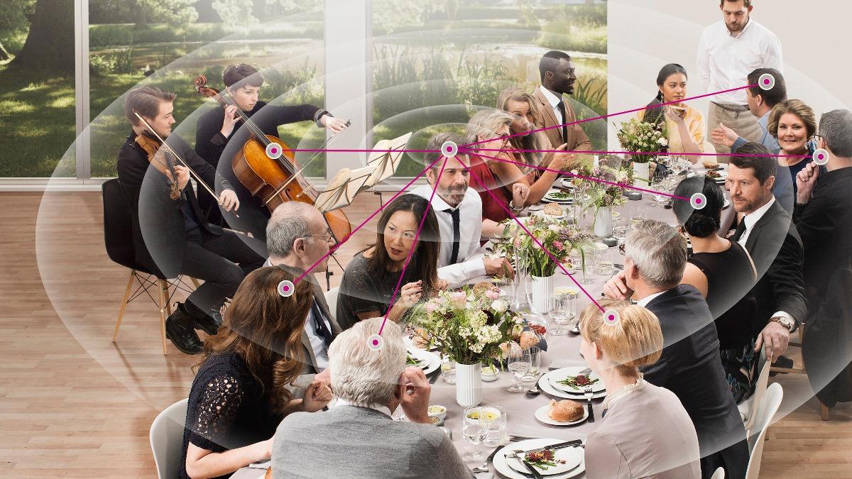 En festlig middag med gæster, der nyder mad og musik i en lys, moderne spisestue med udsigt til haven.