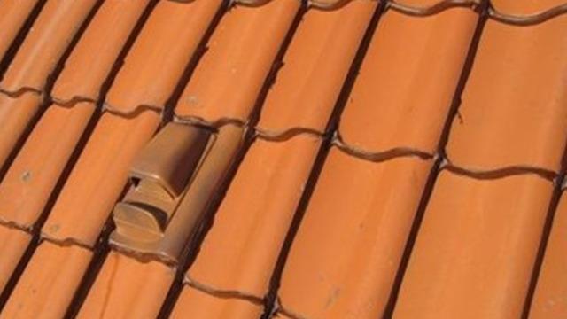 Tage med terracotta tagsten i orange farve, der viser en del af taget med en tagsten i midten.