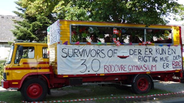En farverig lastbil med banner, der siger "Survivors of 3.0" og dekorationer til en festlig begivenhed.