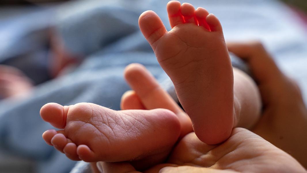 Toes på en nyfødt baby, der hviler i en voksen hånd, med bløde tæer og en uskyldig stemning.