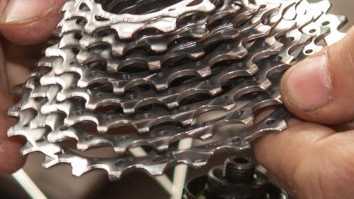 Hånd, der holder en stak cykelklinger i metal, der viser detaljer og tekstur af gearsystemet.