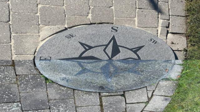 Kompasrose indlejret i fliser, viser retningerne nord, syd, øst og vest.