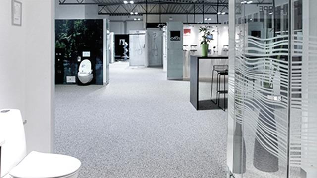 Moderne badeværelseudstilling med toilet, brusekabiner og stilfuld indretning i en rummelig butik.