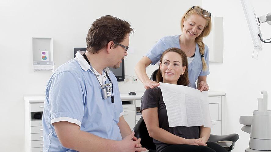 En tandlæge og en assistent forbereder en patient til behandling i en moderne tandklinik.