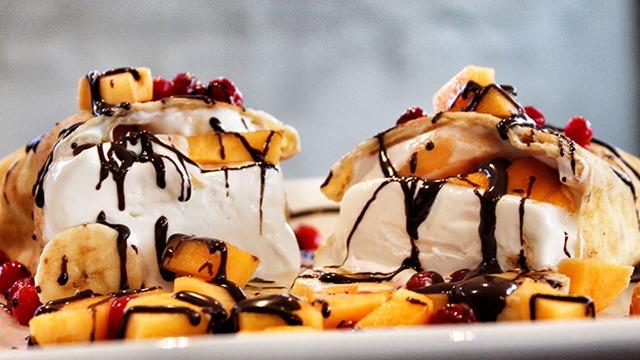 Lækre desserttallerkener med is, frugt og chokoladeovertræk.