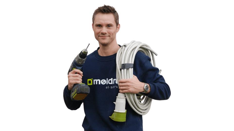 En mand holder en boremaskine i den ene hånd og en slange i den anden, iført en sweatshirt med logo.