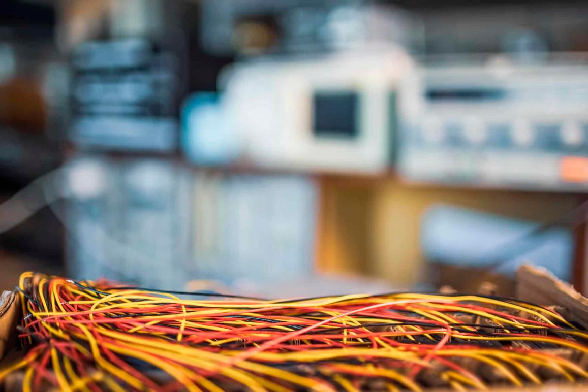 Farverige ledninger i en kasse med sløret baggrund af elektronisk udstyr.