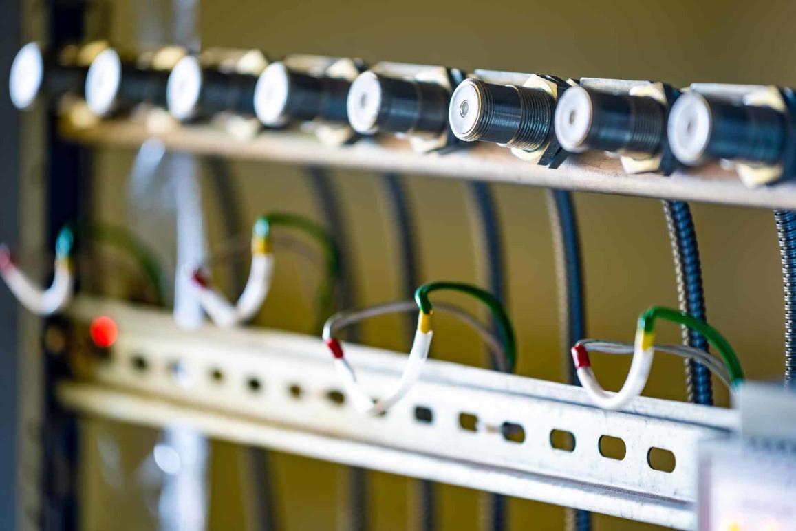 Nærbillede af en metalramme med trykmålere og farvede ledninger til elektrisk installation.