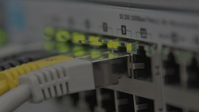 Nærbillede af en netværks-switch med tilsluttede ethernet-kabler og lysdioder, der indikerer forbindelse.