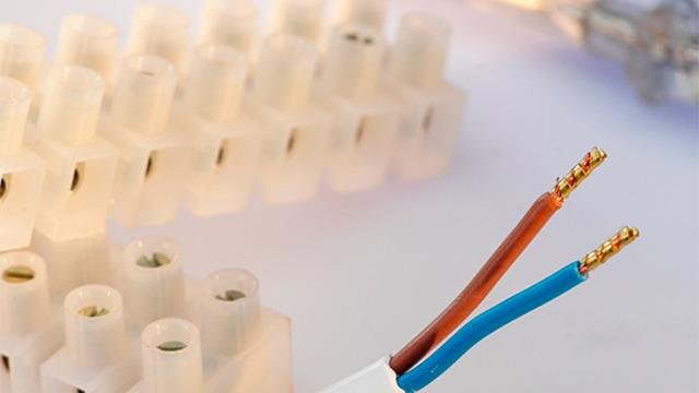 Kabel med brune og blå ledninger ved siden af transparente stikforbindelser på en lys overflade.
