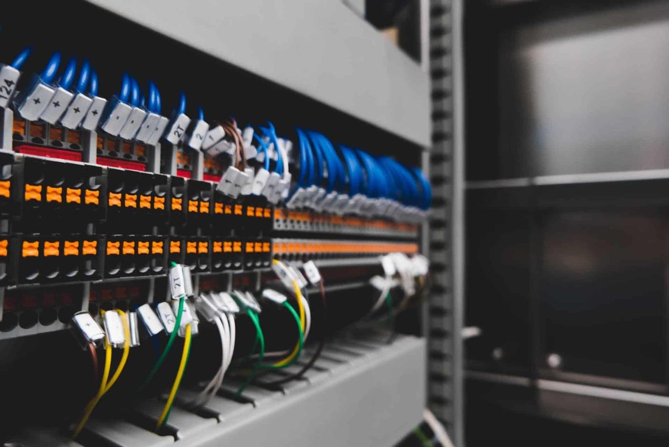 Et skab med elektriske ledninger og forbindelser, der viser farverige kabler og komponenter i et teknisk miljø.