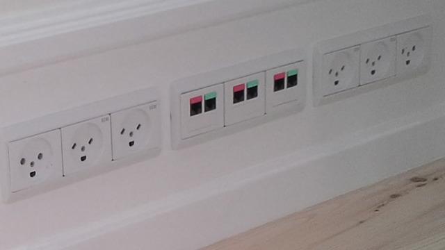 Tre vægudtag med forskellige stik og farvekoder til elektriske forbindelser.