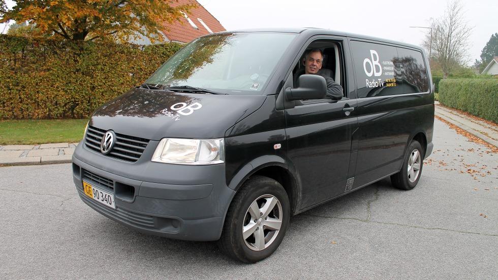 En sort Volkswagen varevogn parkeret på en vej med en chauffør i førersædet.
