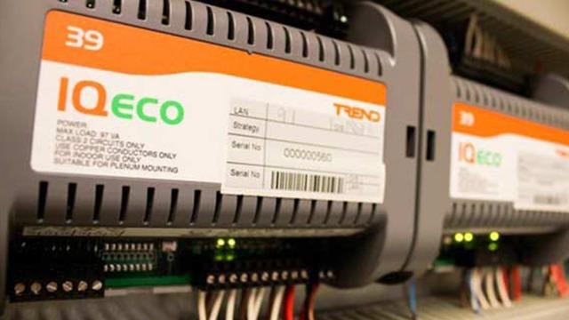 To udstyr med IQeco og Teno mærkater, der er installeret i en elektrisk tavle med ledninger.