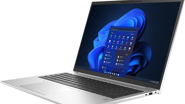 En bærbar computer med Windows 11 på skærmen, placeret på en hvid overflade.