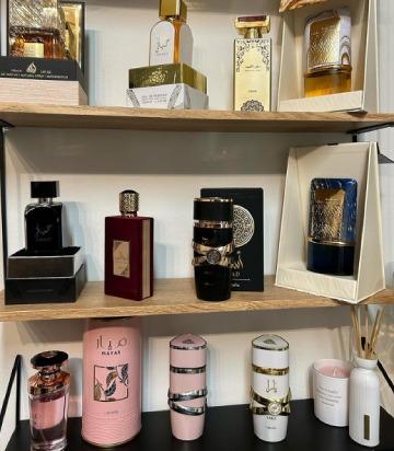 Flere parfumer i elegante flasker på en hylde, herunder luksuriøse mærker og forskellige farver og designs.