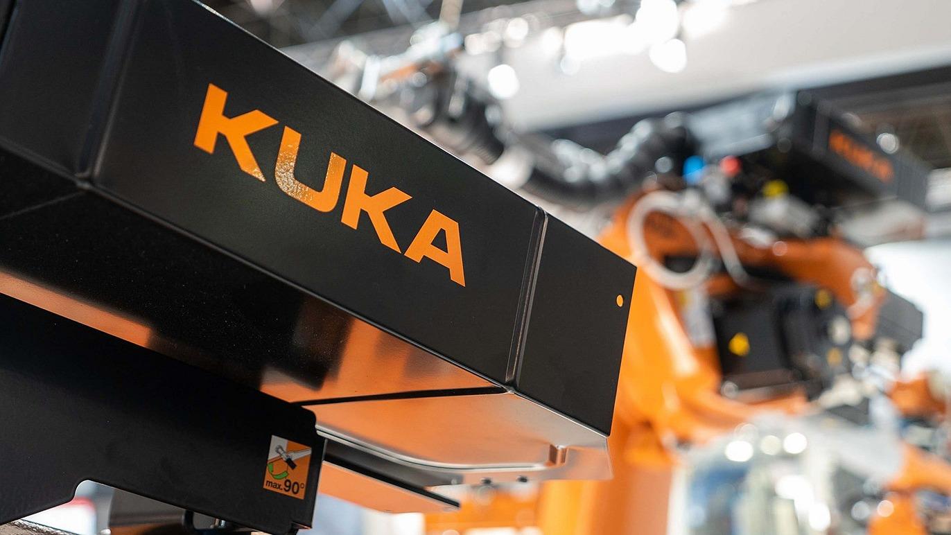 Billede af en KUKA-robotarm med fokus på KUKA-logoet og den orange robotstruktur i baggrunden.