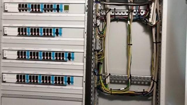 Billede af et elektrisk skab med sikringer og kabler organiseret i et system.