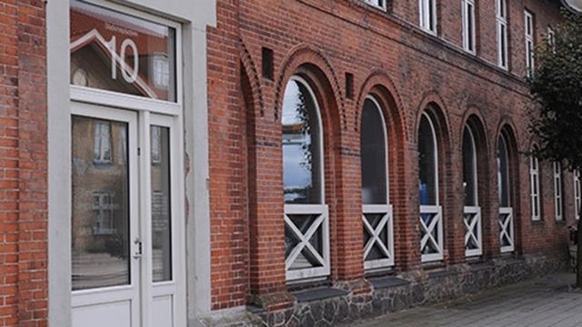 En murstensbygning med buede vinduer og en hvid dør, nummer 10, i en bygade.