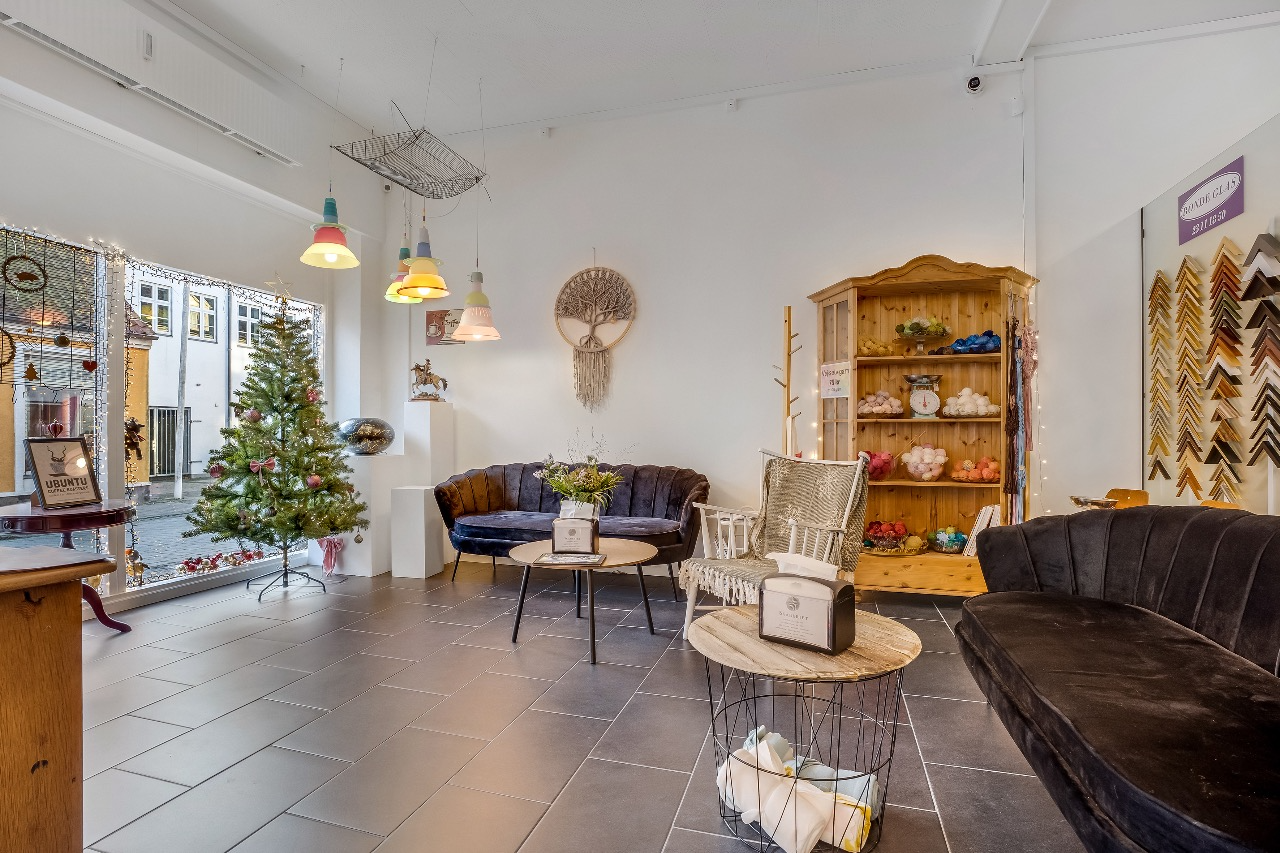 En hyggelig indretning med sofaer, et træbord, en juletræ og en smuk udstilling af håndværk.