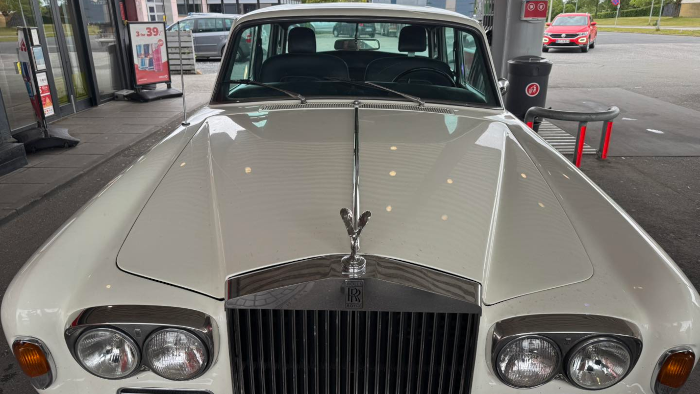 En klassisk hvid Rolls-Royce bil set forfra med en karakteristisk kølerfigur og skinnende overflade.