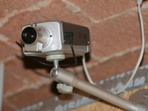 Overvågningskamera monteret på væggen med en metalarm, der holder det i en garage.