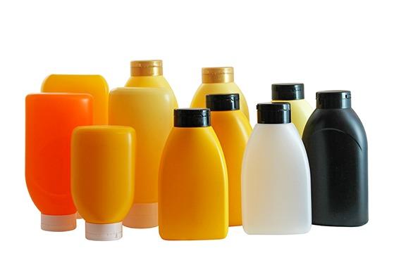 Flere farverige plastikflasker i forskellige former og størrelser, herunder gule, orange og sorte flasker.