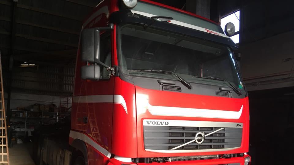 Rød Volvo lastbil parkeret i en garage med dæmpet belysning.