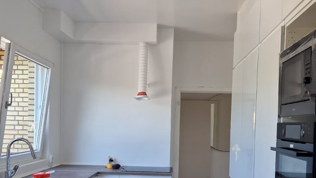 Moderne køkken med hvidt interiør, vindue, og en vægmonteret emhætte.