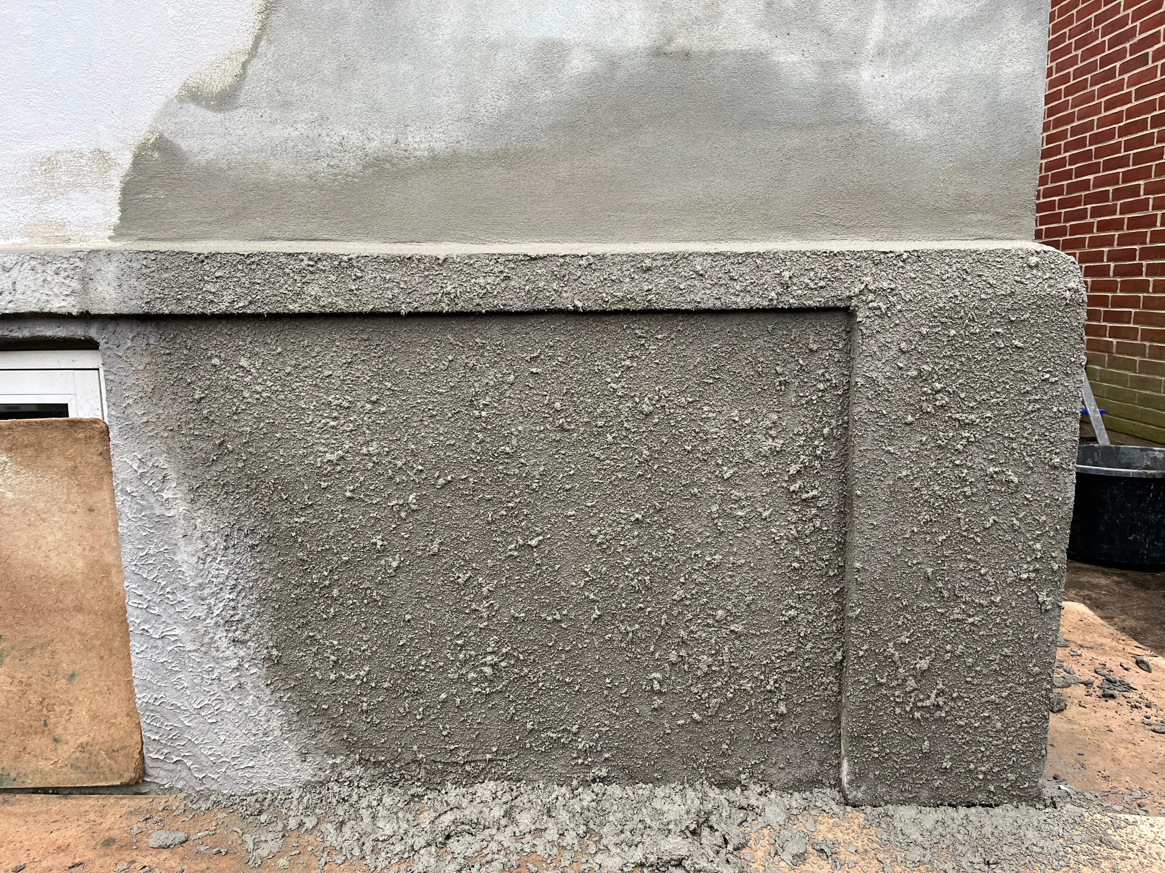 Ny cementpuds på husets fundament med en glat overflade og en skarp kant.