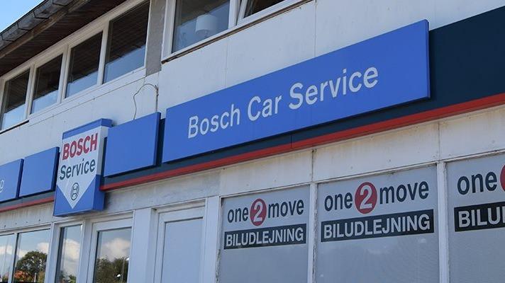 Bosch bilservice facade med skilt og vinduer, der viser biludlejningsfirmaer.