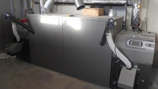 Et moderne varmesystem med to store kedler og rør til ventilation i et rum.