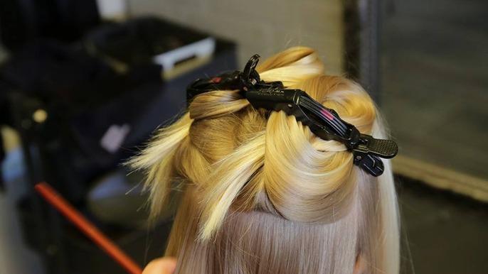 Hårstyling med klips i blont hår, der er opdelt i sektioner til frisering.