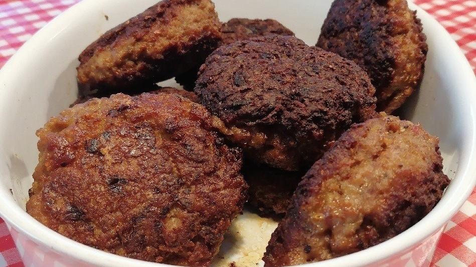 En skål med sprøde frikadeller, der er gyldne og brune, serveret på en ternet dug.