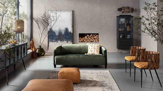 Moderne stue med grøn sofa, brune stole, kunstværk på væggen og en pejs med brænde.